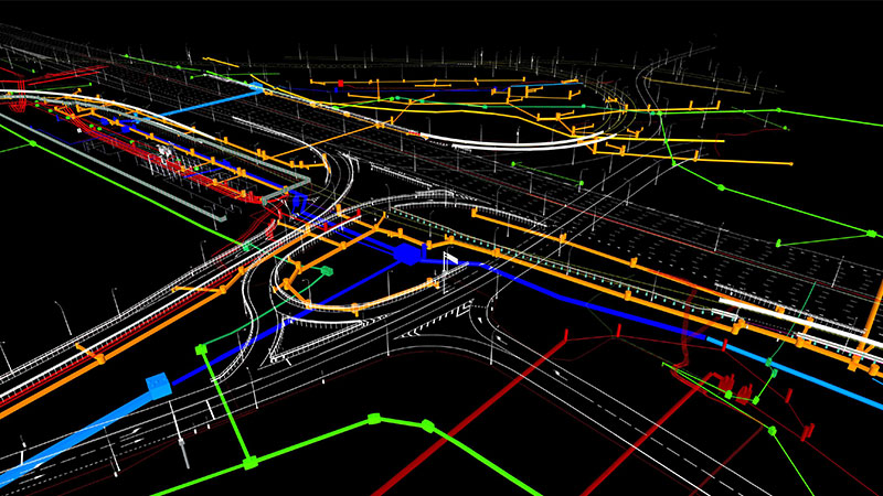 A complex 3D model of an infrastructure layout, featuring coloured lines representing roads, utilities, or construction plans, intersecting and running in various directions.