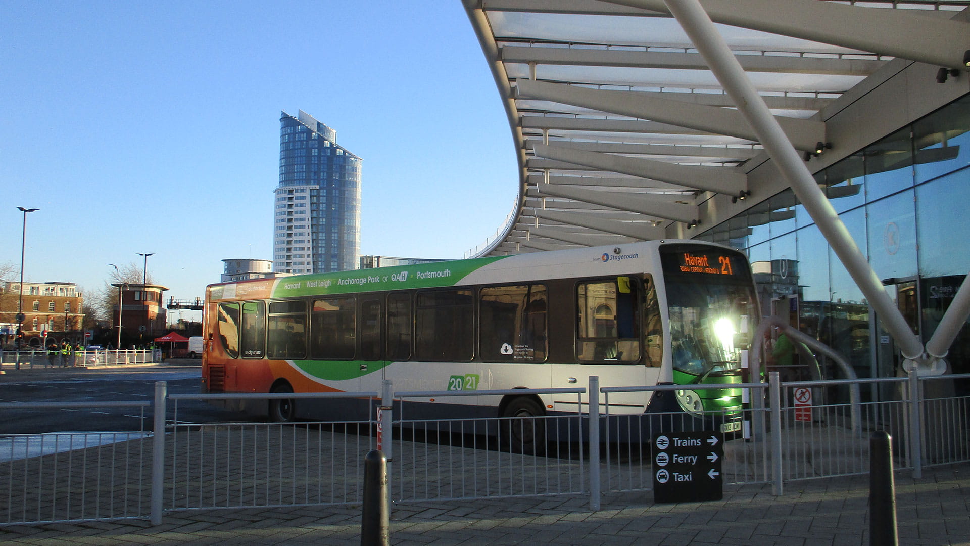 Bus stop parked in a bus bay next to a large building which is Portsmouth bus station.  